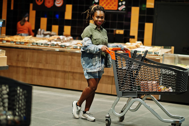 African american woman with shopping cart trolley in the superma - Φωτογραφία, εικόνα
