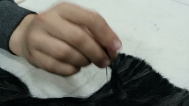 A mão de um adolescente trabalha com feltro. Agulha para fazer pinturas a partir de lã. Enchimento padrão de feltro preto em uma base de tecido branco. Artesanato artesanal
. - Filmagem, Vídeo