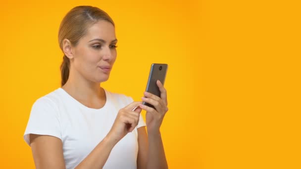 Attractive female scrolling smartphone, surprised by new online application - Séquence, vidéo