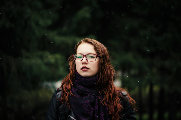 Belle jeune fille aux cheveux roux sur fond vert naturel. Des flocons de neige tombent. Cheveux roux, peints au henné
. - Photo, image