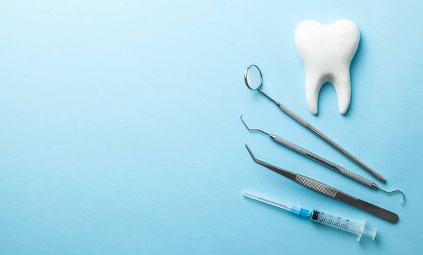Instrumentos dentários e dentários em fundo azul. Tratamento dentário. Ferramentas dentárias espelho, gancho, pinças, seringa. Espaço de cópia para texto
. - Foto, Imagem