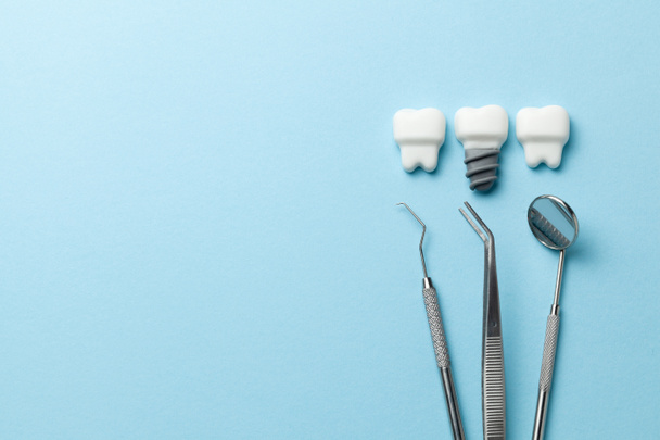 gesunde weiße Zähne und Implantate auf blauem Hintergrund und Zahnarztwerkzeugspiegel, Haken. Kopierraum für Text. - Foto, Bild
