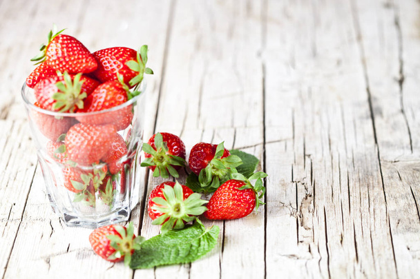 Organic red strawberries in glass and mint leaves on rustic wood - Fotoğraf, Görsel