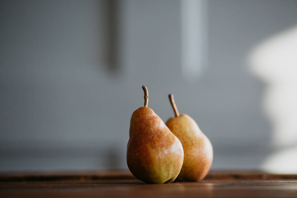 Beautiful ripe tasty pears on a large kitchen wooden table with a garland of lights. A beautiful screen saver for an article about wholesome food, a concept for a food blog, a saver for a pastry chef - Fotoğraf, Görsel