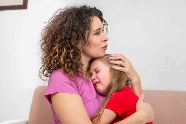 Genç bir anne küçük kızını sakinleştirir. Kız ağlıyor. - Fotoğraf, Görsel