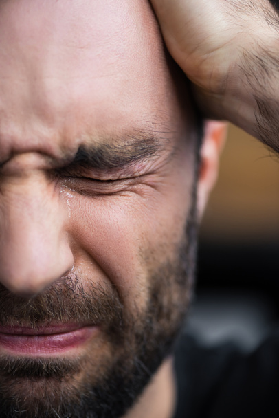 частковий вид на пригніченого бородатого чоловіка, що плаче закритими очима
  - Фото, зображення