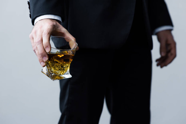 vista recortada del hombre adulto en traje negro sosteniendo vaso de whisky
 - Foto, Imagen