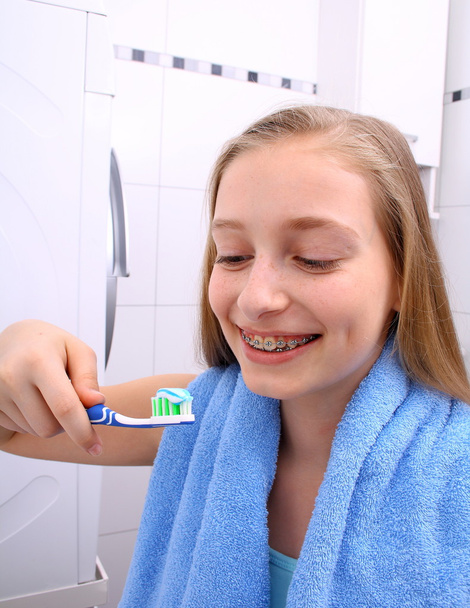 Fille blonde avec des bretelles souriant tout en se brossant les dents
 - Photo, image
