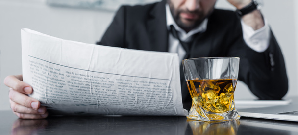 częściowy widok biznesmen czytania gazety w pobliżu szkła whisky - Zdjęcie, obraz