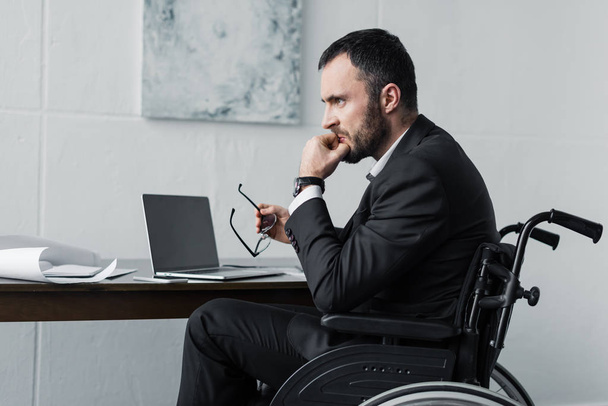 empresario discapacitado decepcionado sentado en silla de ruedas en el lugar de trabajo
  - Foto, Imagen