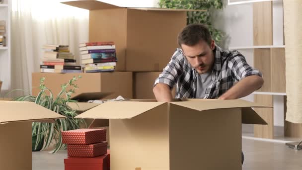 Angry man moving home after divorce boxing belongings and taking off wedding ring - Filmmaterial, Video