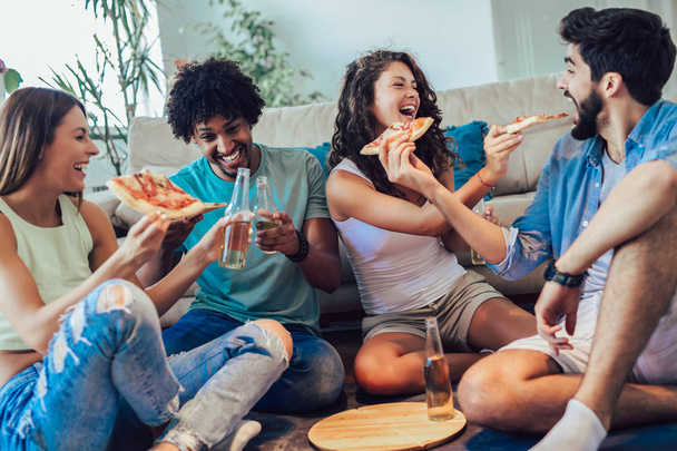 Group of young friends eating pizza.Home party. - 写真・画像