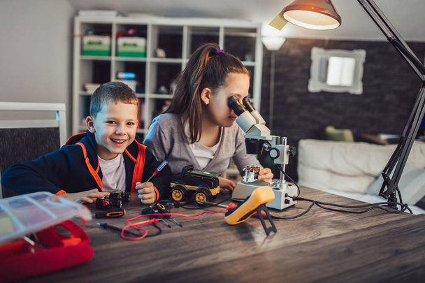 glücklich lächelnde Jungen und Mädchen konstruieren technisches Spielzeug und machen Raub - Foto, Bild
