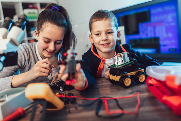 Happy smiling boy and girl constructs technical toy and make rob - Foto, imagen