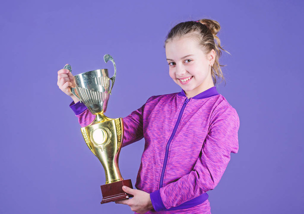 Sport achievement. Celebrate victory. Girl hold golden goblet. Importance of capturing evidence of kids progress. Proud of her achievement. Celebrating childrens achievements great and small - Valokuva, kuva