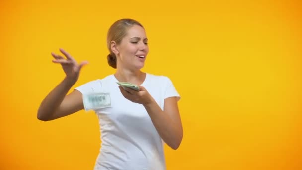 Carefree woman throwing dollars around, rich female wasting money, consumerism - Materiał filmowy, wideo