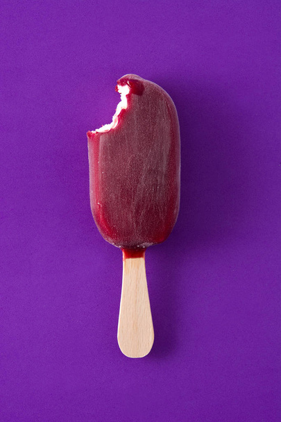 Bitten strawberry popsicle on violet background. Top view. Copyspace - Foto, Imagem