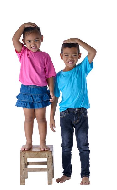 Kleine jongen en meisje hun hoogte geïsoleerd op witte bac meten - Foto, afbeelding
