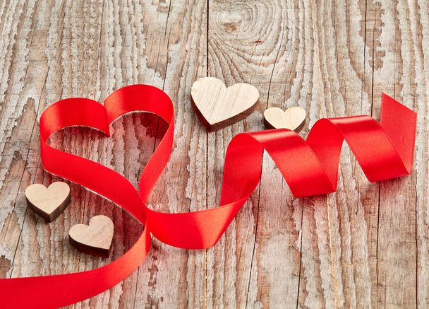 Red curled ribbon in heart shape, on wooden background - Photo, Image