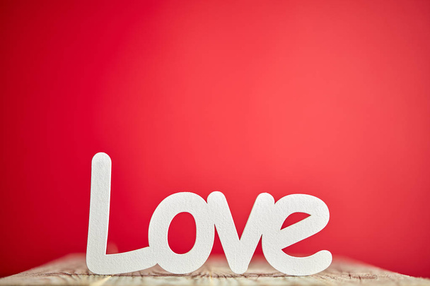 Λευκό σημάδι αγάπης σε ξύλινο τραπέζι και κόκκινο φόντο  - Φωτογραφία, εικόνα