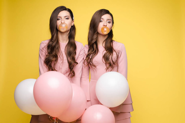 Giovani gemelli che tengono in mano palloncini rosa e bianchi
. - Foto, immagini