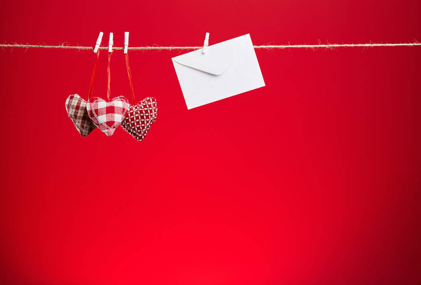 Three plush hearts on a red background and envelope  - Photo, Image