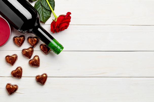 Bottle of red wine on white wooden background with rose and chocolate - Photo, Image