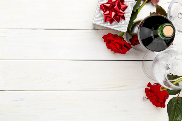 Butelka czerwonego wina na białym tle drewnianych z prezentami i rose-skład - Zdjęcie, obraz
