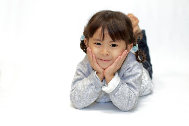 liggende Japanse meisje met de kin rust in handen (4 jaar oud) - Foto, afbeelding
