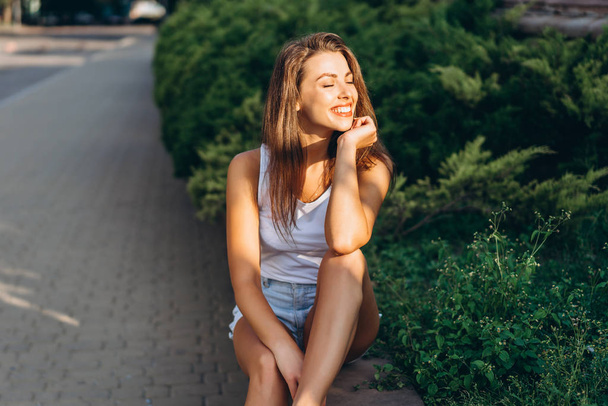 Pretty young smiling brunette girl relaxing outdoor on the stree - Foto, Imagem