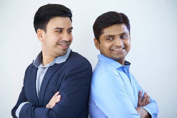 zwei selbstbewusste Manager, die Rücken an Rücken mit einem Lächeln auf weißem Hintergrund stehen - Foto, Bild