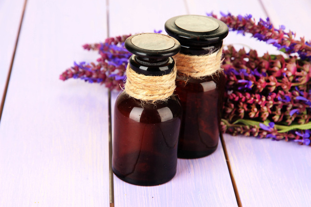 Medicine bottles and salvia flowers on purple wooden background - Photo, Image