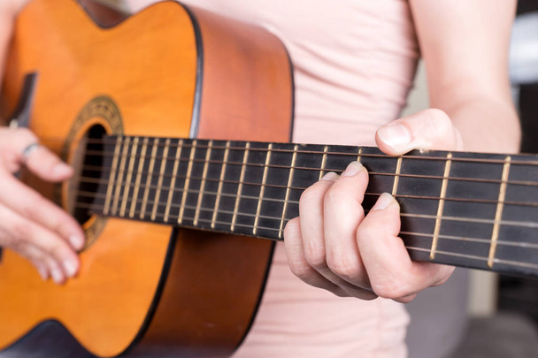 アコースティックギターを弾く若い女性の手のクローズアップ。十代の女の子は歌を再生することを学ぶ - 写真・画像