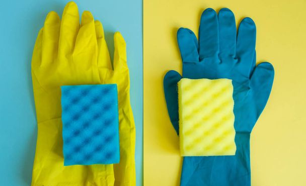 Concept professionnel de nettoyage de maison, accessoires de nettoyage à ressort, deux paires de gants et d'éponges en caoutchouc sur fond double jaune-bleu, pose plate
 - Photo, image