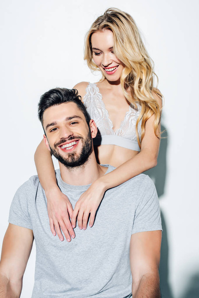 happy blonde girl looking at handsome and cheerful man on white  - Fotoğraf, Görsel