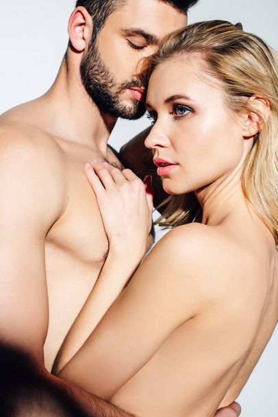 naked blonde girl touching handsome shirtless boyfriend on white  - Fotó, kép