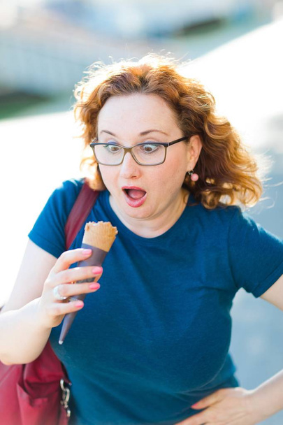 Überraschte Frau in blauem T-Shirt schaut auf Eistüte - Foto, Bild