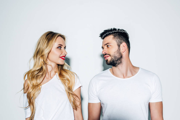 handsome man and attractive blonde woman looking at each other on white  - Foto, imagen