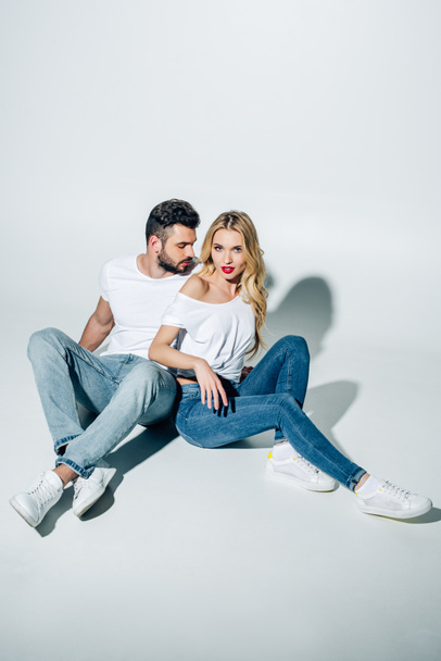 handsome man sitting and looking at attractive blonde girl on white  - Foto, immagini