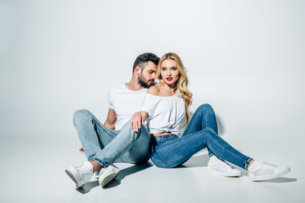 handsome bearded man sitting and looking at attractive blonde girl on white  - Foto, imagen