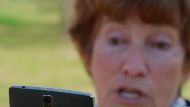 Крупним планом старша жінка розмовляє через мобільне відео, емоції, зосереджується на мобільному. Бабуся спілкується через смартфон на відкритому повітрі. Сучасний спосіб життя літніх людей на пенсії. Активна літня леді, використовуючи мобільний телефон, розмовляє через додаток Messenger. Усміхнена бабуся
 - Кадри, відео