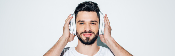 panoráma lövés vidám ember megható fejhallgató hallgatása közben zenét, és mosolyogva fehér  - Fotó, kép