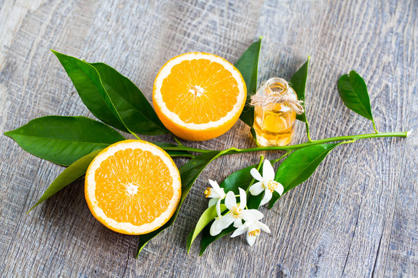 Juicy Orange iki bölümden kesilmiş ve neroli, portakal ağacının çiçekleri, rustik ahşap arka plan üzerinde. Portakal çiçeği Narenciye kokulu çiçek parfüm ve çay, afrodizyak kullanılır. - Fotoğraf, Görsel