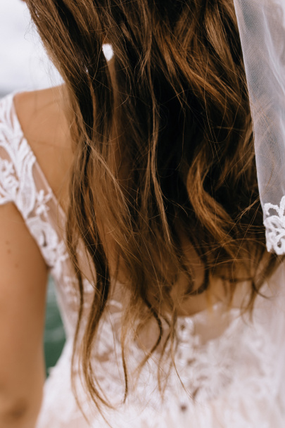 bruid terug in kant jurk met een boeket - Foto, afbeelding