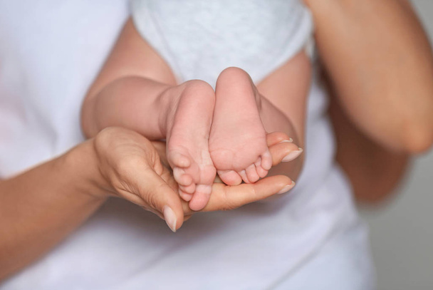 Mother holding feet of her cute little baby in hands, closeup - Foto, Imagem