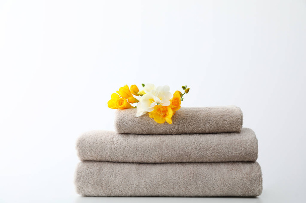 Stack of fresh towels with flowers on table against white background - Foto, immagini