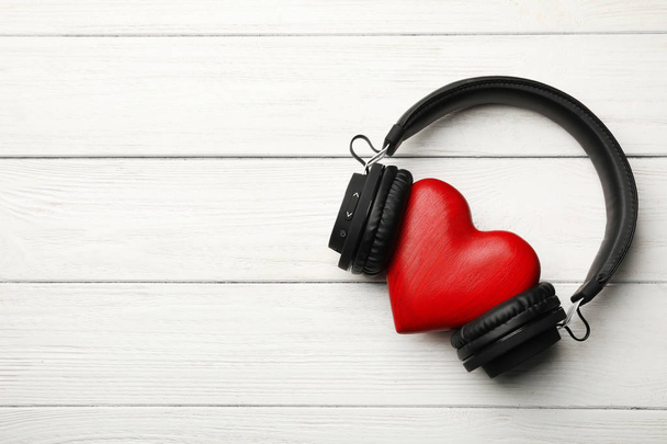 Decorative heart with modern headphones on wooden background, top view. Space for text - Foto, imagen