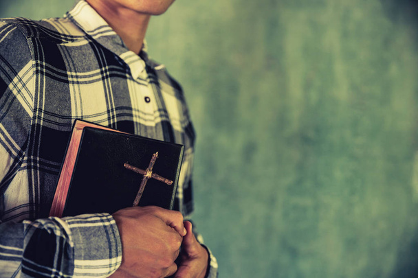 Egy fiatalember, aki Bibliát tart kezében - Fotó, kép