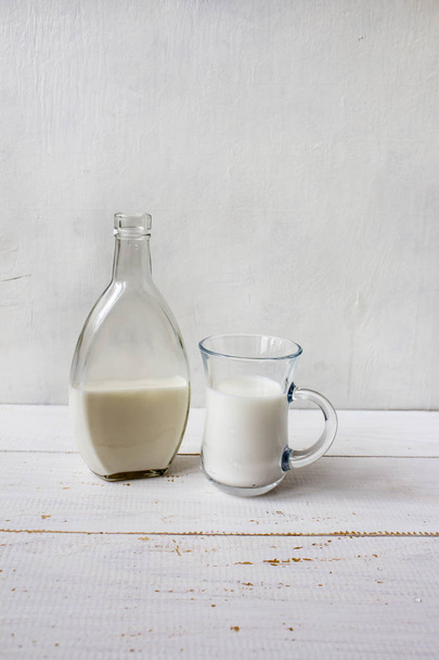 Herkullista tuoretta maitoa valkoisella puupohjalla. Pullo m
 - Valokuva, kuva