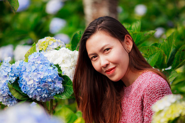 A woman wearing a red shirt in a hydrangea garden and having fun - Photo, Image